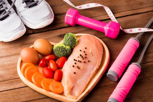 Top view of Raw chicken breasts fillets no boneless with spices in heart plate wood and sport or athlete's equipment dumbbell
running shoes on wooden background, Healthy lifestyle diet food concept