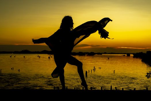 A beautiful latin model is silhouetted as she poses with the rising sun behind her on a exotic Caribbean beach
