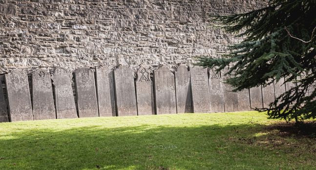 Dublin, Ireland - February 13, 2019: Tombstones laid against a wall in the cemetery at Arbor Hill next to the Church of the Sacred Heart on a winter day