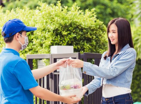 Asian young delivery man wear face mask he making grocery service giving rice food boxes plastic bags to woman customer receiving door at house after pandemic coronavirus, Back to new normal concept