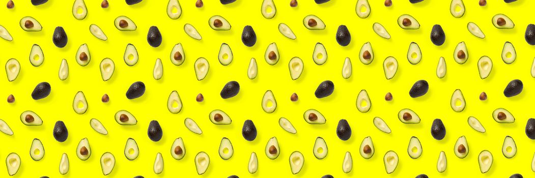 Avocado banner. Background made from isolated Avocado pieces on yellow background. Flat lay of fresh ripe avocados and avacado pieces