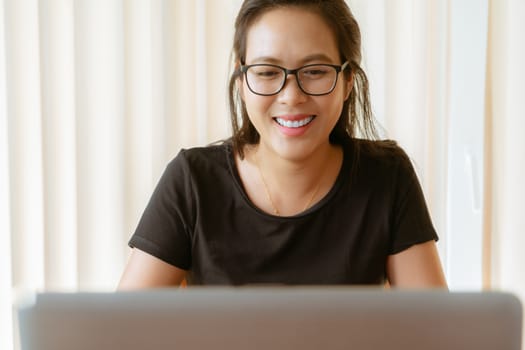 happy woman using laptop. Young Asian woman sitting at home and working on laptop