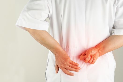 senior doctor woman suffering of backache, touching back with hand, muscular pain over white background