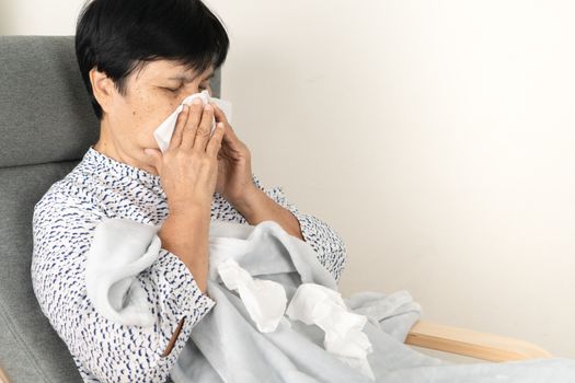 sick senior woman with dirty tissue. ill person wearing blanket woolen lay down on sofa