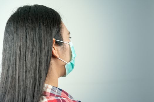 rear view of woman in mask because of air pollution and epidemic in city. Protection against virus, infection, exhaust and industrial emissions