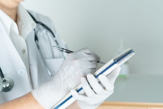 female doctor writing medical information in notebook at hospital