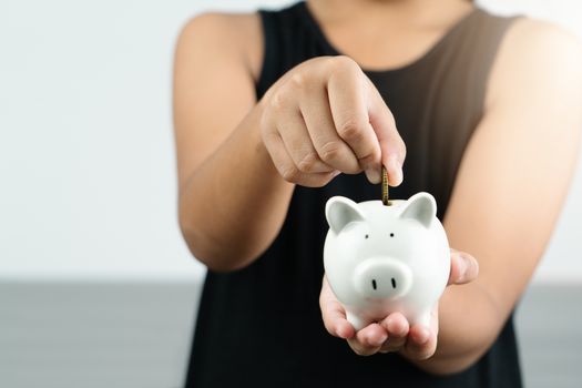 Money saving and donation concept, child put money on cute white piggy bank