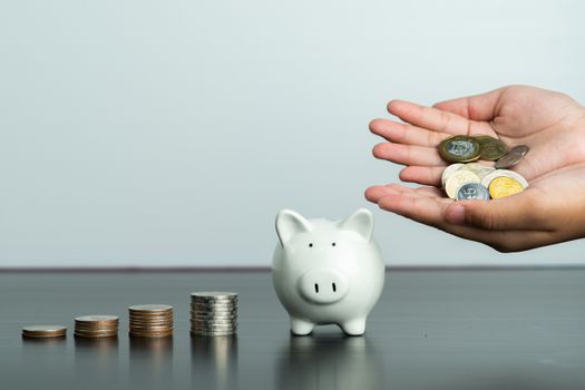 Money saving and donation concept, child put money on cute white piggy bank