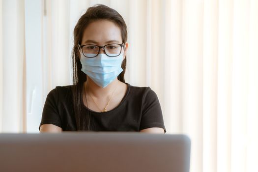 working from home during Coronavirus or Covid-19 outbreak, woman with face mask protection while working at home
