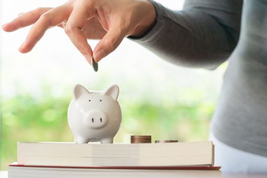 woman putting a coin to saving piggy bank, saving money for education concept