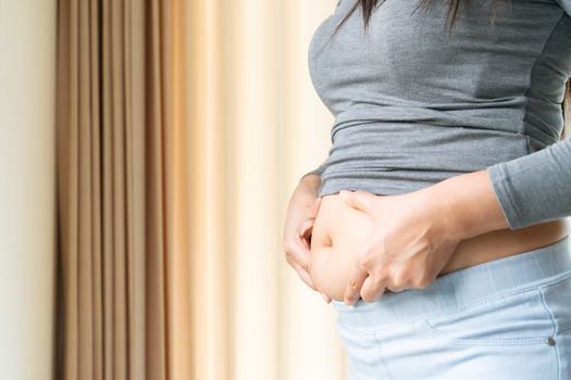young woman's belly, women touch her fat belly, woman diet lifestyle concept