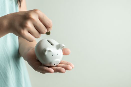 Saving and business concept, girl with piggy bank and coins at home