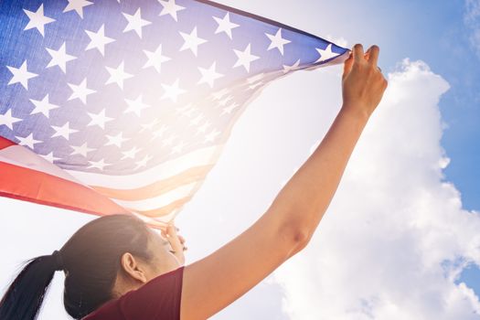 woman holding United States of America flag on sunny sky. USA Memorial day and Independence day concept.