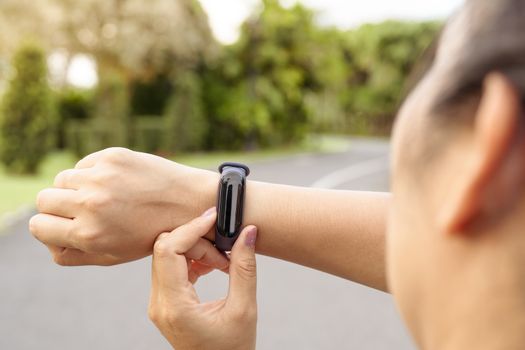 fitness woman runner setting up smart watch before running. Outdoor exercise activities