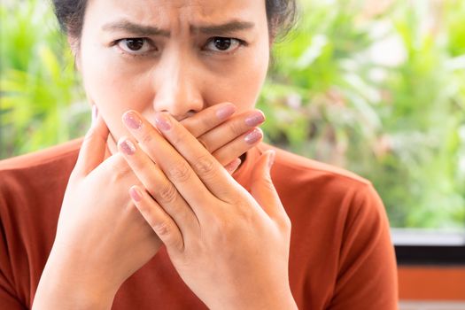 Woman with bad breath covering mouth, halitosis concept