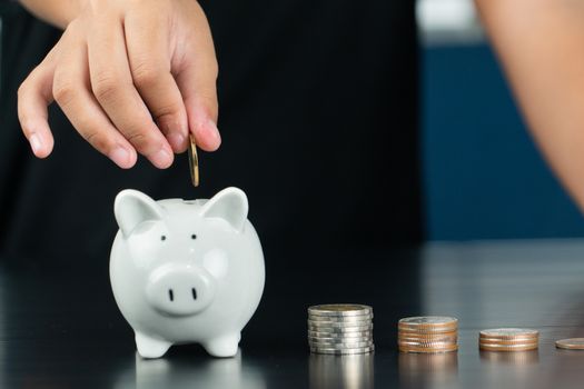 Money saving and donation concept, child put money on cute white piggy bank