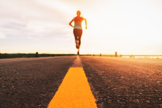 Athlete running on the road trail in sunset training for marathon and fitness. motion blur of woman exercising outdoors