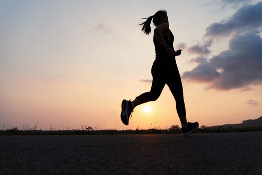 sport woman running on a road. Fitness woman training at sunset
