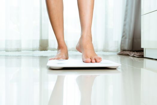 Female leg is stepping on white scales at home