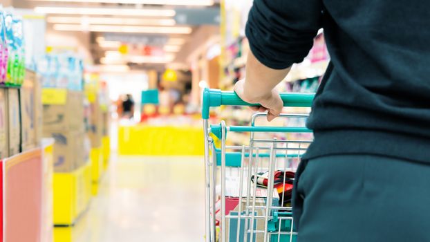 female shopper with trolley with blurred motion of supermarket department store