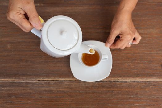 top view of a female pouring tea on wooden table