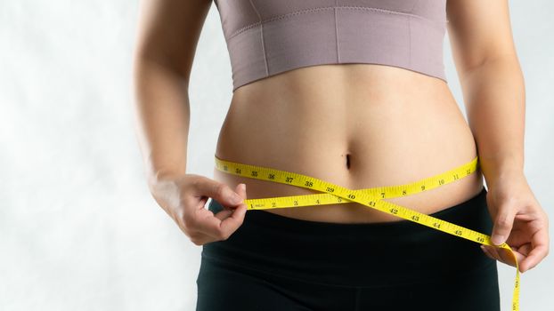 young woman measuring her belly waist with measure tape, woman diet lifestyle concept