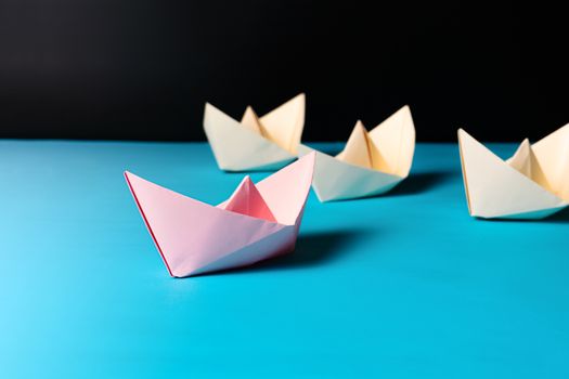 Leadership concept, pink paper ship lead yellow ship team member
