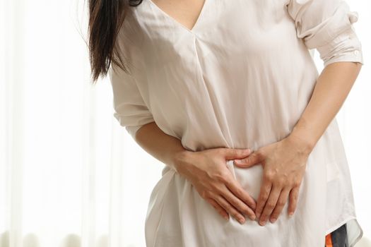 Young woman suffering from abdominal pain feeling stomachache, symptom of pms on white background