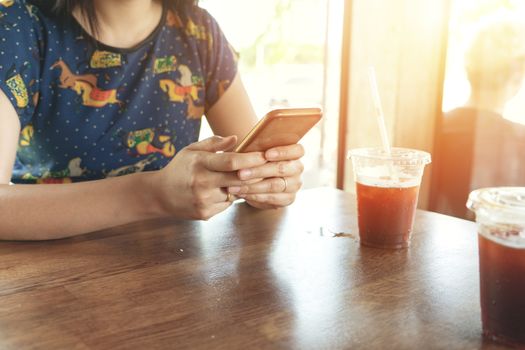 hand holding smartphone searching information on blurred background at coffee shop