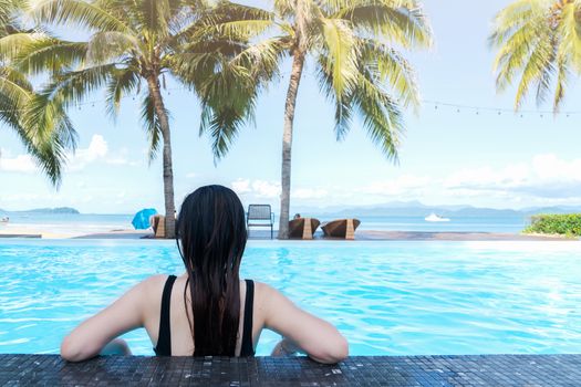 Rear view Asia woman enjoy in the swimming pool