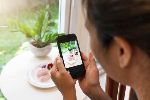 Woman taking a photo of dessert with smartphone