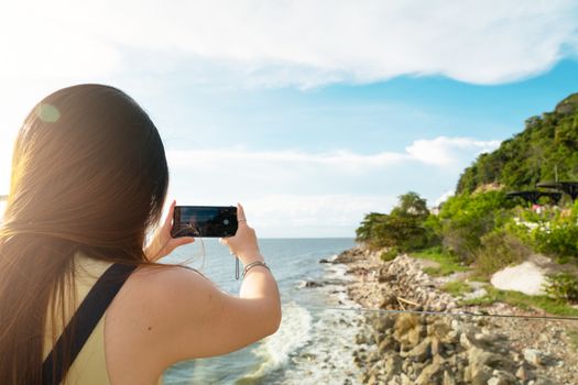 Travel lifestyle. Female tourist taking photo of beautiful beach on smartphone