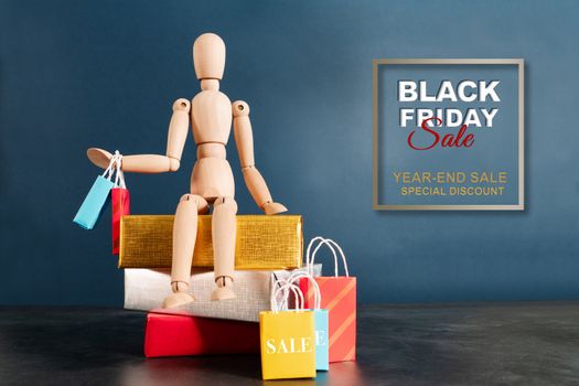 Black Friday sale, wooden doll sitting on shopping cart with shopping bag