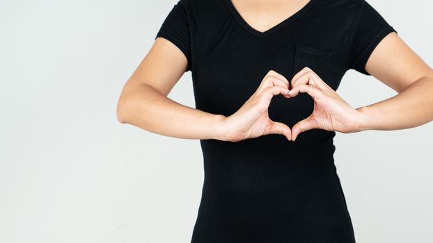 World heart day concept of woman making a heart gesture with her fingers in front of her chest showing her love