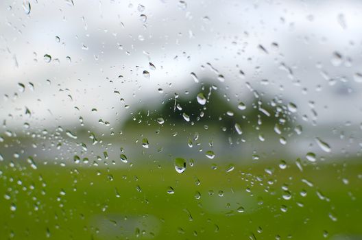 Rain falling on a window pane. Water droplets background. Water drop falling down on the window glass in rainy weather. Rain drops on rainy day on outside window glass
