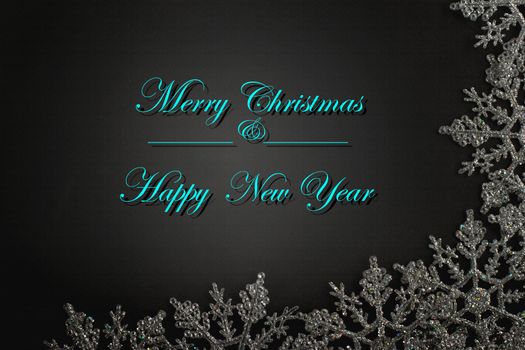 Merry Christmas and Happy New Year text in turquoise blue with silver Christmas snowflake frame on black background. Winter holidays card concept. Mock up, banner