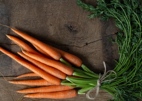 Fresh organic carrots on antique wooden table. Rustic kitchen concept. Banner, poster, mock up. Grunge, vintage, rustic style