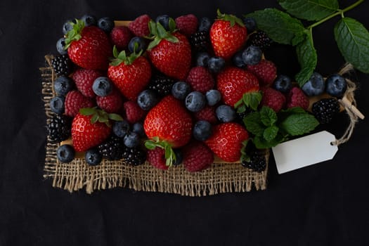 Strawberries, blackberries, rasberries, green mint on canvas black bakground. Mock up, menu, cafe poster concept