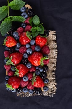 Strawberries, blackberries, rasberries, green mint on canvas black bakground. Mock up, menu, cafe poster concept