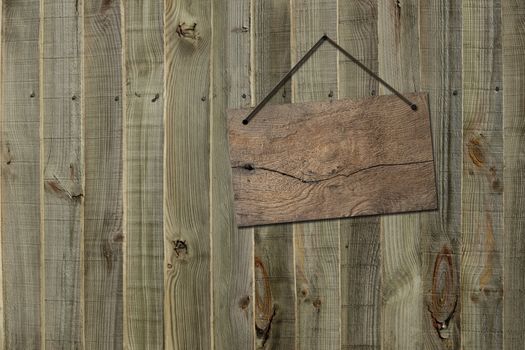 Antique rustic wooden blank sign board hanging on old weathered fence background. Mock up, board concept