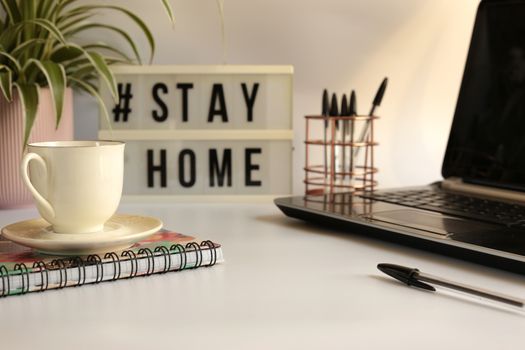 Home office desc concept during self quarantine as preventive measure against virus. Stay safe concept. Cup of coffee, clock, stationary, home plant on white background