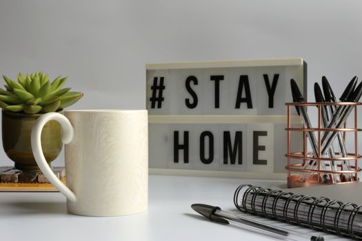 Home office desc concept during self quarantine as preventive measure against virus. Stay safe concept. Cup of coffee, clock, stationary, home plant on white background