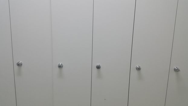 Perspective view of lockers or cupboards in a row with white doors, keys and locks