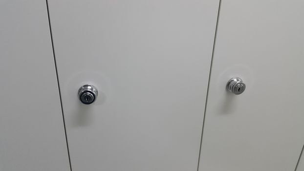 Perspective view of lockers or cupboards in a row with white doors, keys and locks