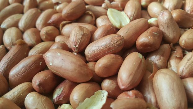 Closeup view of mixed, dried, roasted  peeled and unpeeled peanuts. A fruit for background text
