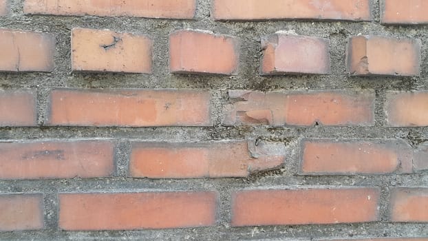 Closeup texture of red brick wall. A background of a weathered old exterior brick wall in the sunshine.
