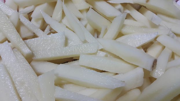 Closeup view of uncooked potato french fries or potato sticks with copy space for text