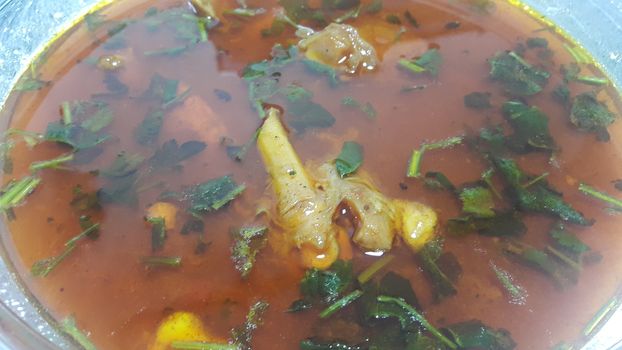 Top view of siri paaye or paya dish garnished with diced ginger, long coriander leaves and fresh sliced lemon. This dish is popular in Pakistan and Bangladesh
