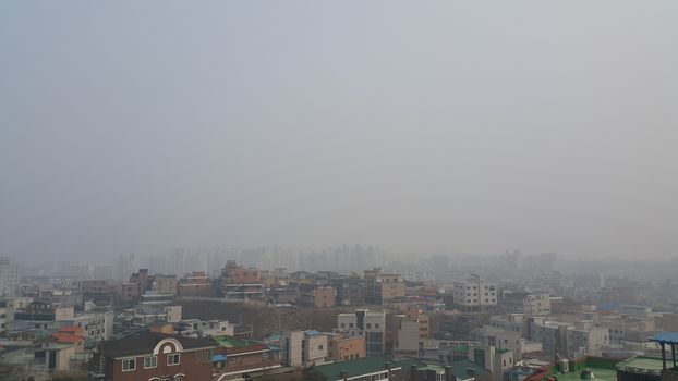 Cityscape aerial view of developed country with  dusty, smogy or amoky background in the sky and skyscraper buildings.