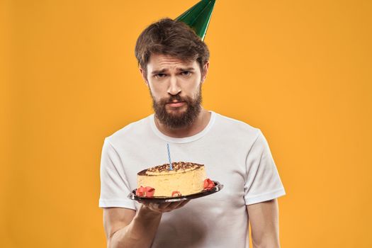 A bearded man with a cake and in a cap celebrating his birthday. High quality photo